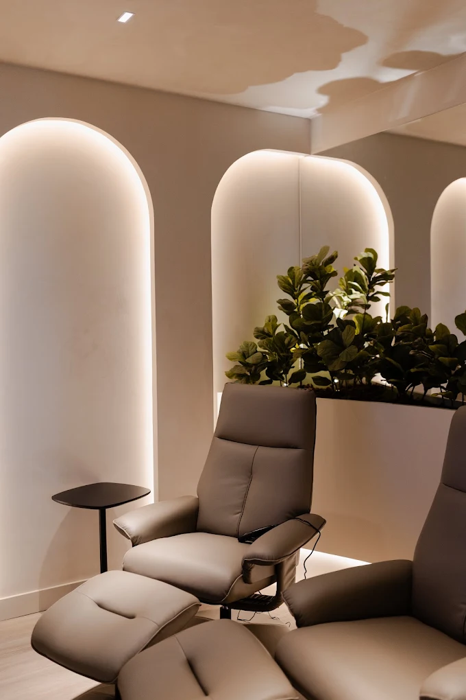Poltronas de espera sob arcos com iluminação indireta na Clínica Balma